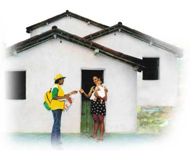 Foto de uma agente comunitária de saúde conversando com mulher em frente a uma casa. Nota-se que a mulher tem um bebê no colo e que, há outras casas atrás daquela em destaque.