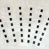 Nesta foto, pequenos quadrados pretos sobre fundo branco formam um agrupamento. Nota-se que foram colocados de maneira a originarem linhas verticais, em forma de leque.
