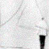 Esta foto em preto e branco mostra um grande muro branco todo rabiscado, aleatoriamente. No canto inferior direito, nota-se um homem em pé.