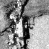 Esta foto tem grande parte tomada pela cor preta. A única fração em que se vê alguma coisa é no quadrante superior, preenchido pelo desenho, na cor branca, de uma pessoa em pé. Notam-se também traços brancos formando círculos que envolvem o indivíduo.