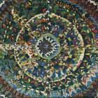 Mandala formada por círculos crescentes. A imagem é toda colorida por pequenas pinceladas, onde predominam as cores azul, amarela e vermelha. O branco surge para enfatizar os traçados dos círculos, delimitando cada camada. 