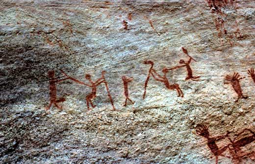 Nesta imagem, pinturas rupestres indicam duplas em que uma das pessoas, com os braços estirados, toca a outra.